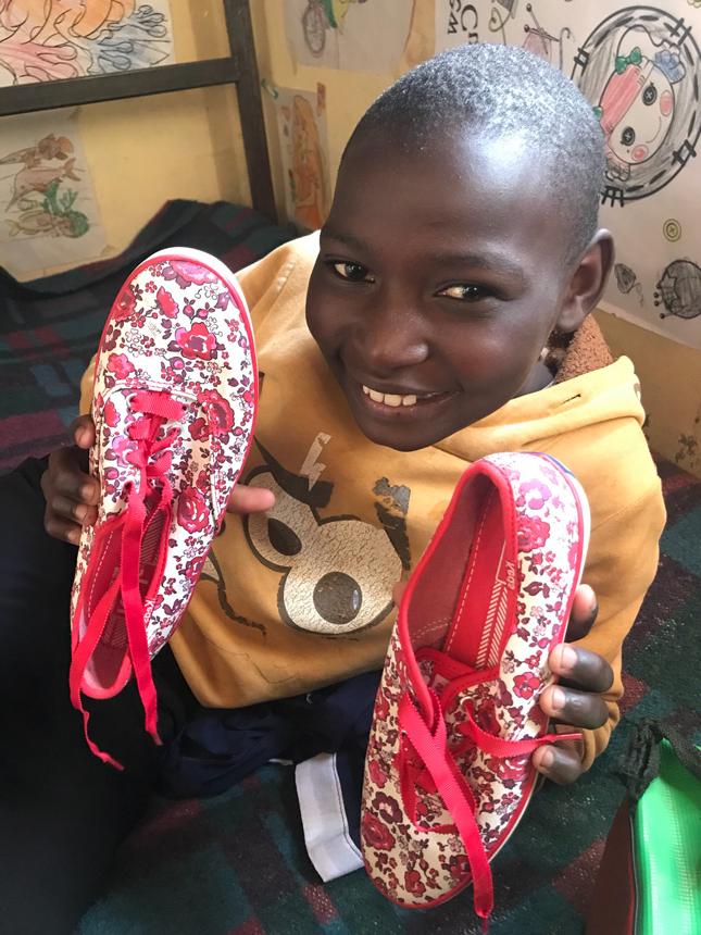 Kenyan child holding a new pair of shoes